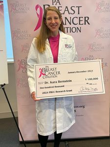 photo of Kara Bernstein and lab members holding a large $100,000 check at the PA Breast Cancer Coalition award ceremony. 
