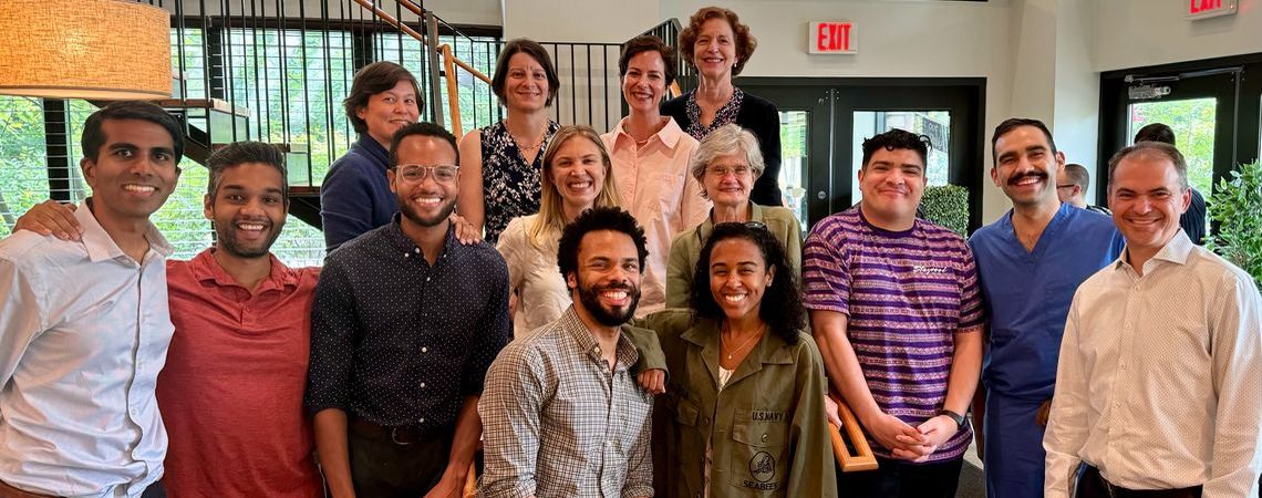 A group of students and mentors standing in the lobby of a restaurant
